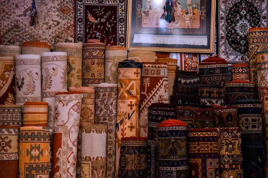 Vibrant collection of traditional rolled carpets on display in a cultural bazaar setting.